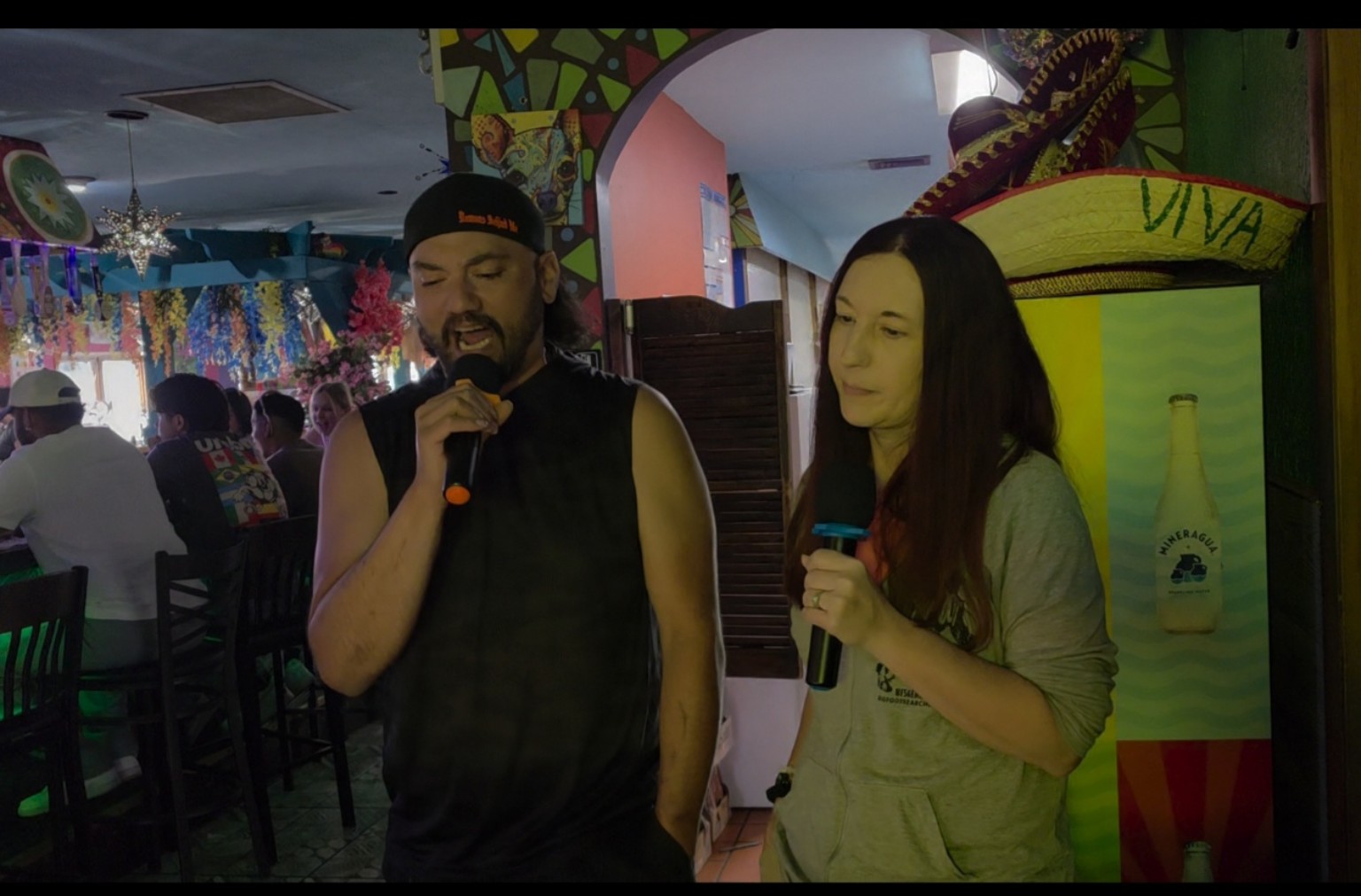 A man and woman singing karaoke together at Los Cabos